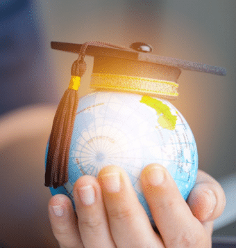 hand of a person carrying globe which is covered with graduation cap